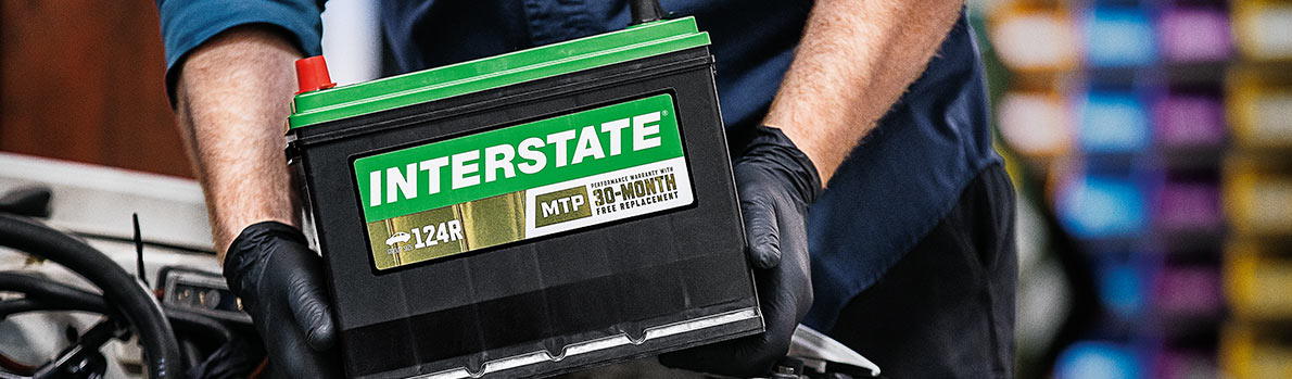 Imagen de mecánico sosteniendo una batería de Interstate